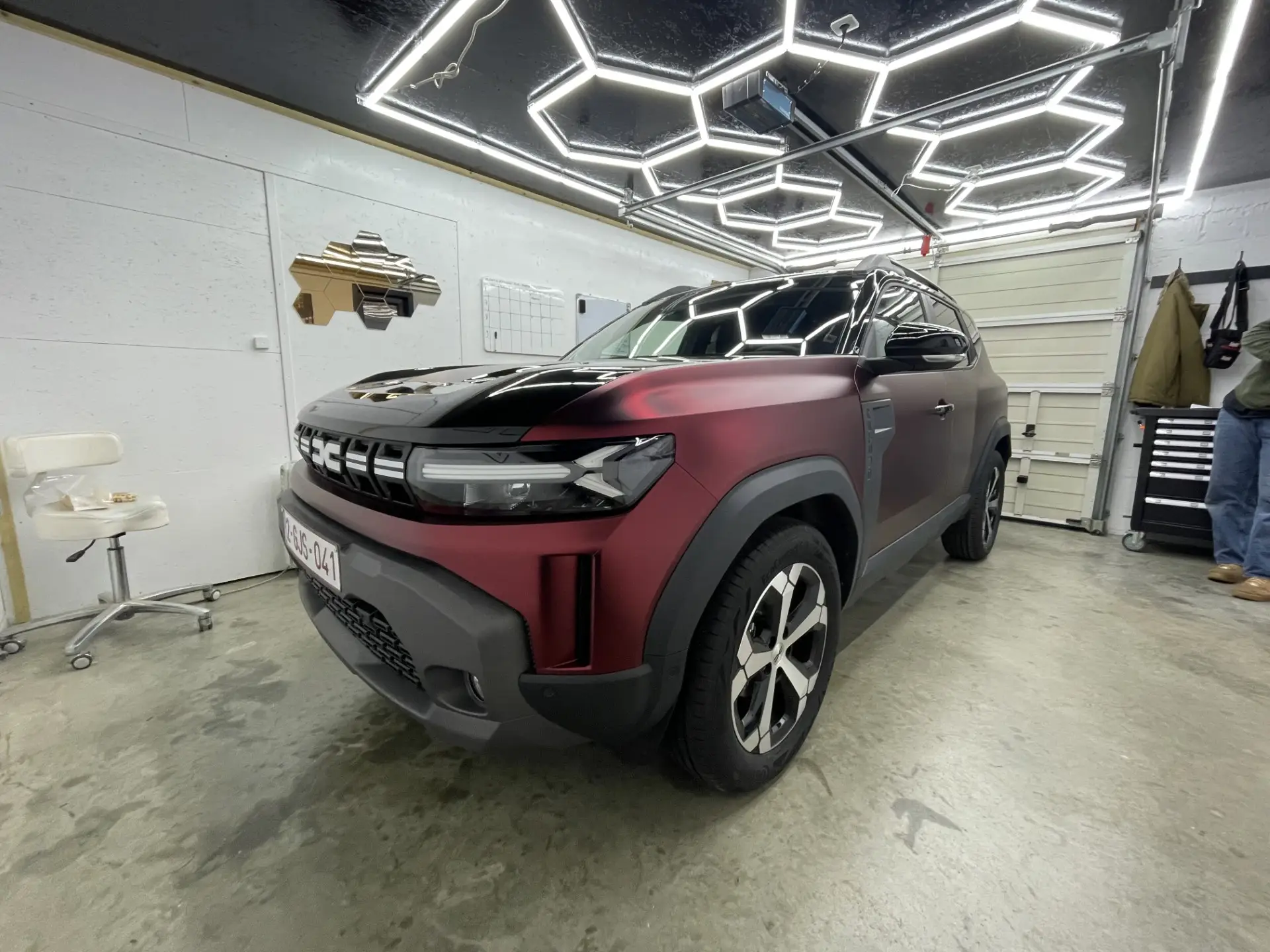 Dacia Duster in satijnen bordeauxrode wrap met glanzend zwarte motorkap in het atelier