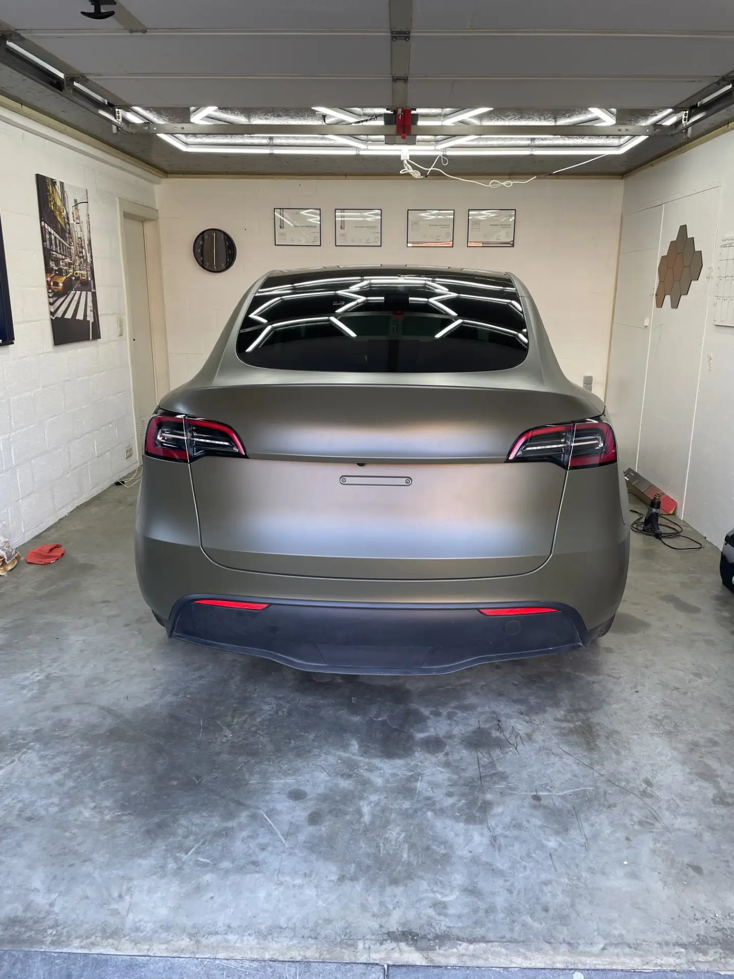 Achterkant van een Tesla Model Y in matgroene wrap in het atelier